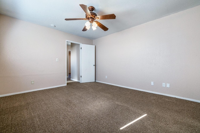 carpeted spare room featuring a ceiling fan and baseboards