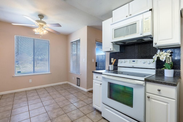 kitchen with light tile patterned floors, white appliances, white cabinets, backsplash, and dark countertops