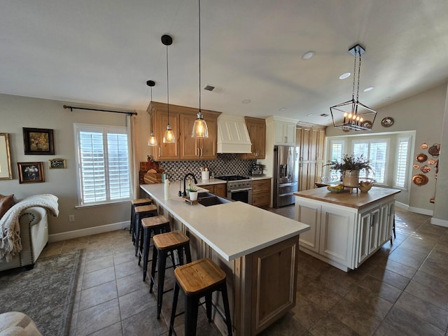 kitchen featuring decorative light fixtures, sink, custom range hood, and kitchen peninsula