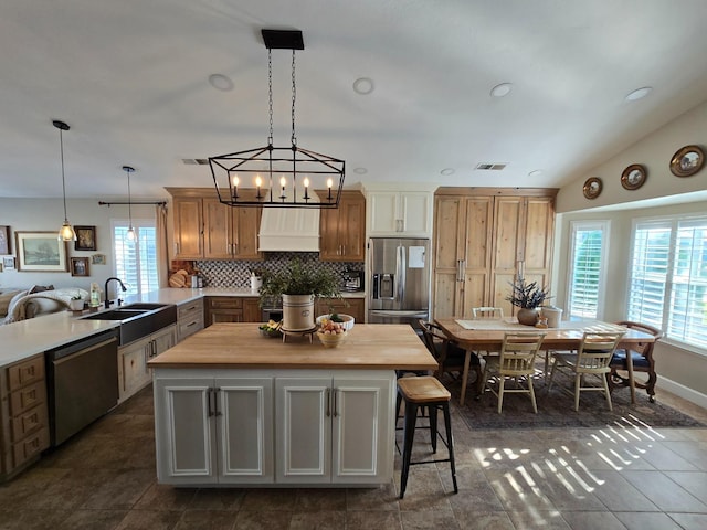 kitchen featuring sink, wooden counters, kitchen peninsula, stainless steel appliances, and custom range hood