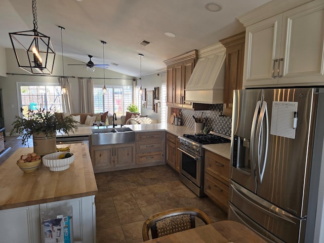 kitchen featuring butcher block countertops, sink, hanging light fixtures, kitchen peninsula, and stainless steel appliances