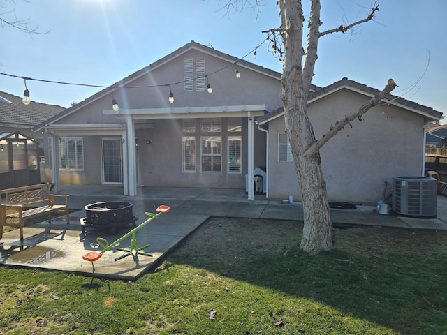 rear view of property with a lawn, a pergola, central AC, a patio, and an outdoor fire pit