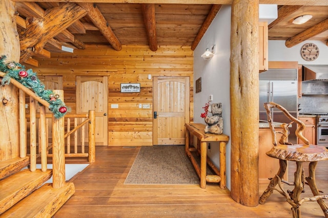 entryway with hardwood / wood-style flooring, wooden walls, wood ceiling, and beam ceiling