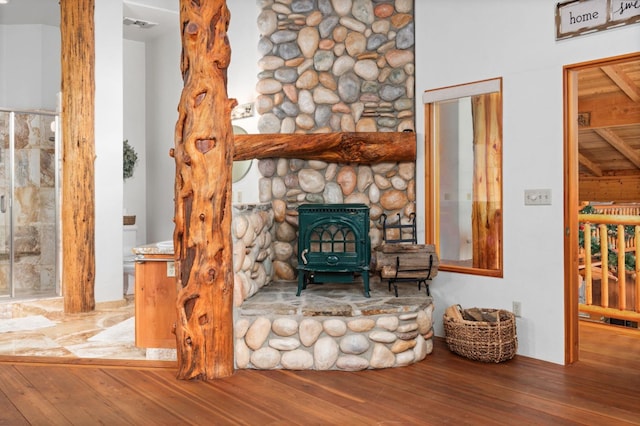 unfurnished room featuring wood-type flooring and a wood stove