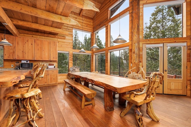 dining space featuring plenty of natural light, wooden ceiling, beam ceiling, and light hardwood / wood-style flooring