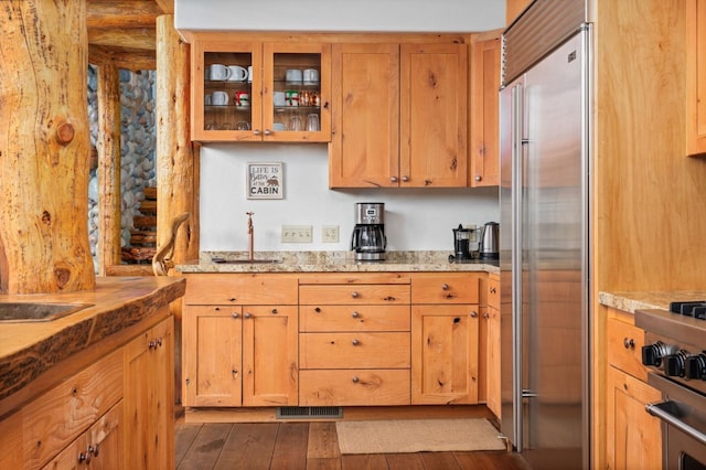 kitchen with light stone counters, dark hardwood / wood-style floors, and built in fridge