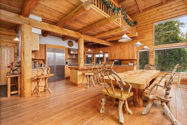 dining space featuring wood ceiling, wooden walls, light hardwood / wood-style flooring, and beamed ceiling