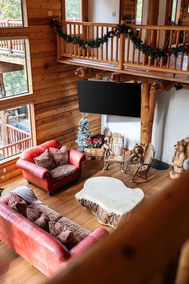 living room featuring wood walls, wood-type flooring, and a high ceiling