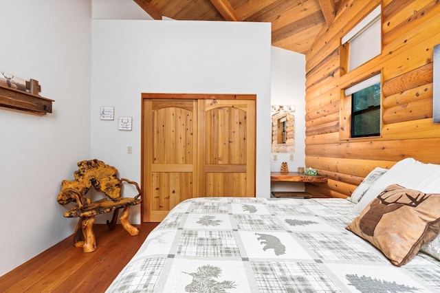 bedroom featuring hardwood / wood-style floors, lofted ceiling with beams, wooden ceiling, and rustic walls