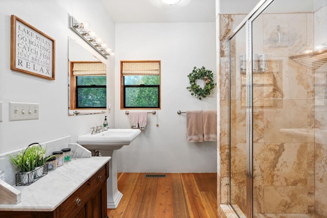 bathroom featuring hardwood / wood-style flooring, a shower with shower door, and sink