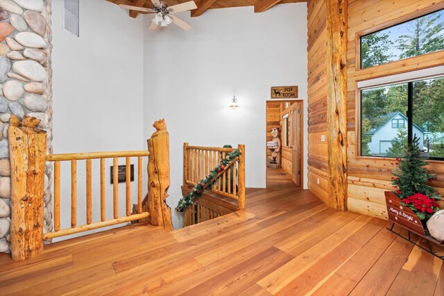 hallway with a high ceiling, wood-type flooring, and beam ceiling