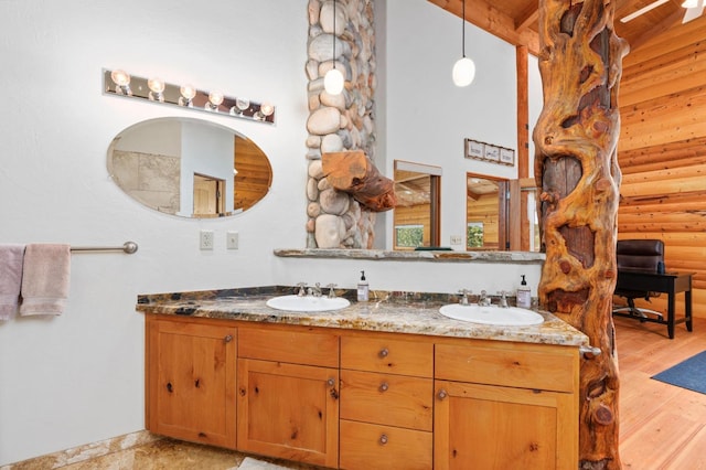 bathroom with hardwood / wood-style flooring, vanity, a towering ceiling, and rustic walls