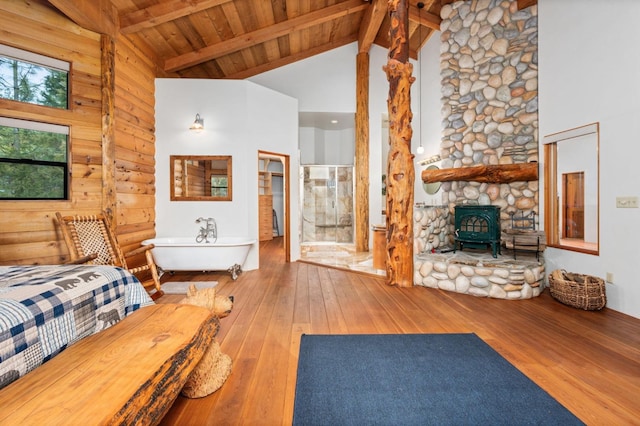 unfurnished bedroom with high vaulted ceiling, a wood stove, hardwood / wood-style flooring, wood ceiling, and beam ceiling