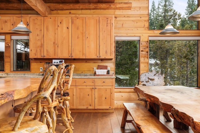 kitchen featuring a healthy amount of sunlight, light hardwood / wood-style flooring, beam ceiling, and decorative light fixtures