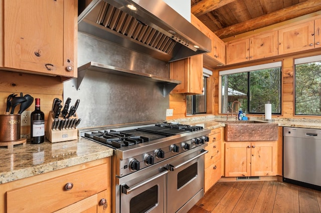 kitchen with wall chimney range hood, sink, stainless steel appliances, beamed ceiling, and light wood-type flooring