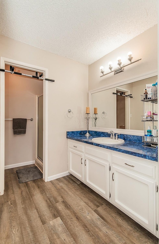 bathroom featuring a shower with door, vanity, hardwood / wood-style floors, and a textured ceiling