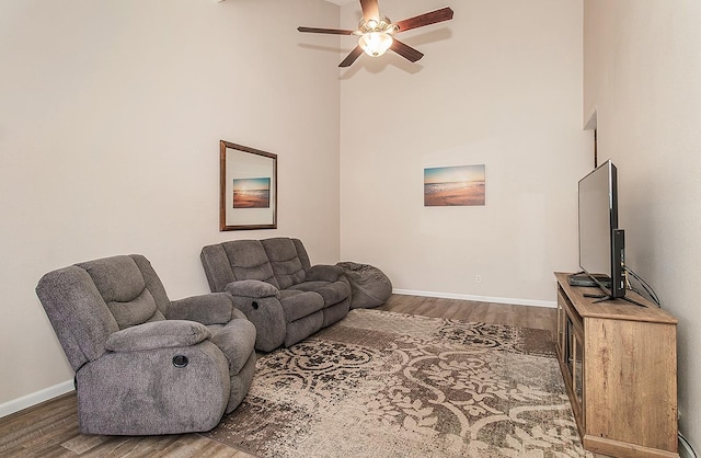 living room with dark hardwood / wood-style flooring, ceiling fan, and a high ceiling