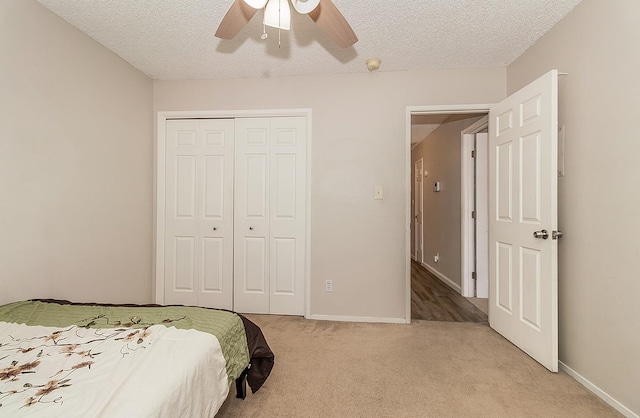 carpeted bedroom with ceiling fan, a closet, and a textured ceiling