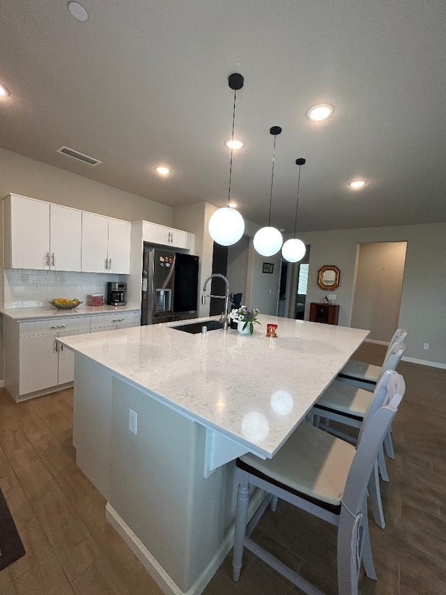 kitchen with white cabinetry, an island with sink, sink, and stainless steel fridge with ice dispenser