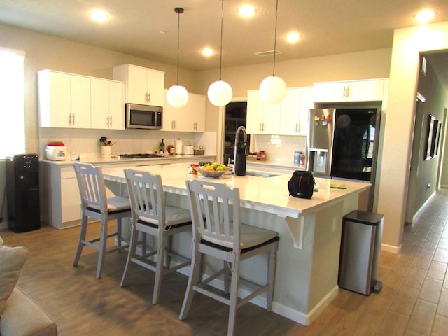 kitchen with white cabinetry, appliances with stainless steel finishes, sink, and a center island with sink