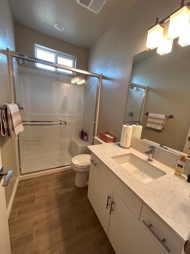 bathroom featuring hardwood / wood-style flooring, vanity, toilet, and walk in shower