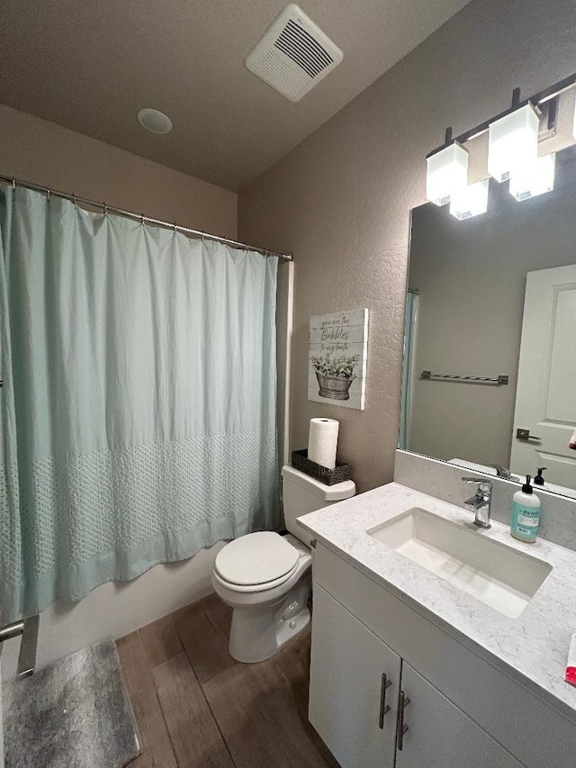 full bathroom with vanity, hardwood / wood-style floors, shower / tub combo, and toilet