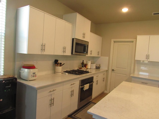 kitchen featuring white cabinetry, tasteful backsplash, and black appliances