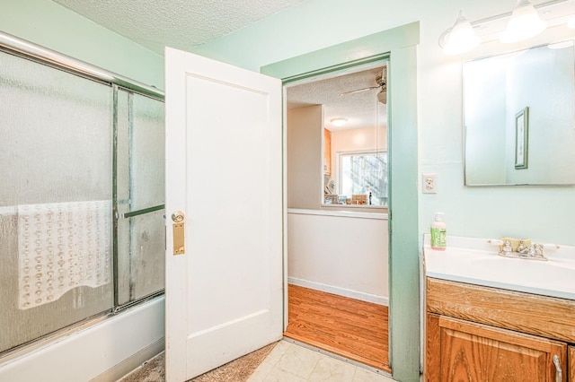 bathroom with vanity, shower / bath combination with glass door, and a textured ceiling