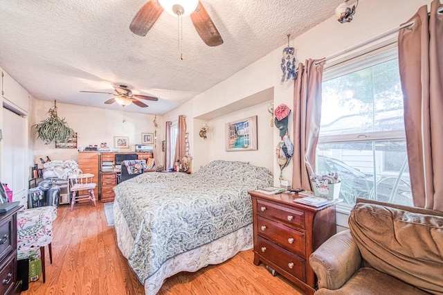 bedroom with ceiling fan, a textured ceiling, and light wood-type flooring