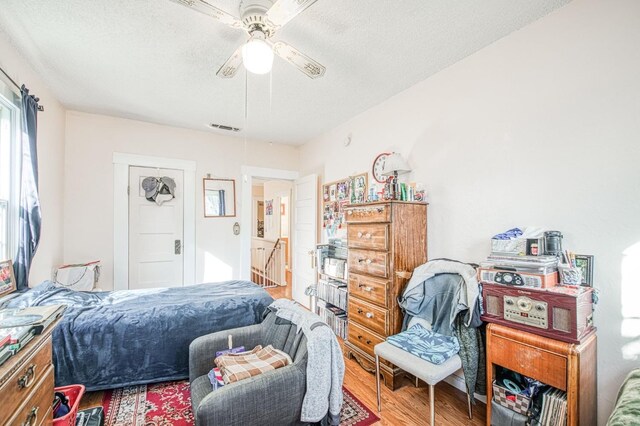 bedroom with ceiling fan, hardwood / wood-style floors, and a textured ceiling