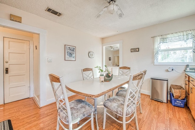 dining space with a textured ceiling, light hardwood / wood-style floors, and ceiling fan