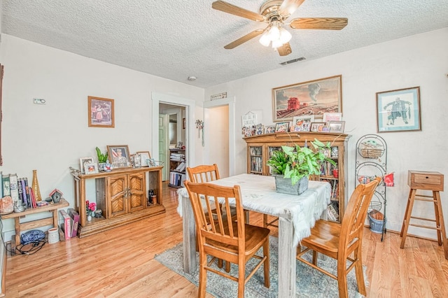 dining space featuring ceiling fan, a textured ceiling, and light wood-type flooring