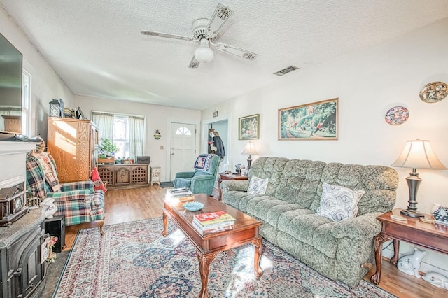 living room featuring ceiling fan, wood-type flooring, and a textured ceiling