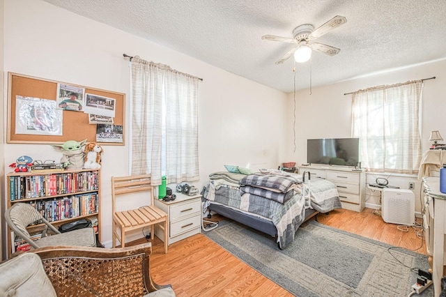 bedroom with ceiling fan, a textured ceiling, and light wood-type flooring