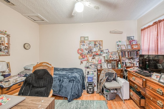 bedroom with ceiling fan, light hardwood / wood-style floors, and a textured ceiling