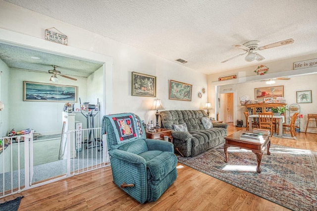 living room featuring hardwood / wood-style flooring, a textured ceiling, and ceiling fan