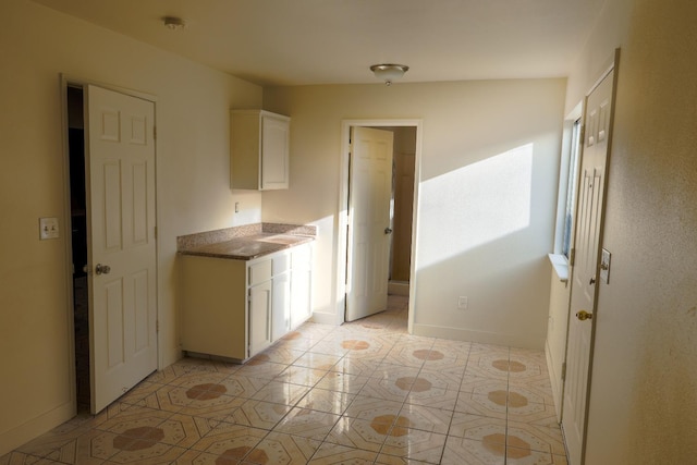 5140 E Belgravia Ave, Fresno, CA 93725 - kitchen with white cabinets, light tile patterned flooring, and baseboards