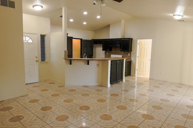 5140 E Belgravia Ave, Fresno, CA 93725 - kitchen with dark cabinetry, decorative backsplash, a peninsula, lofted ceiling, and light tile patterned floors