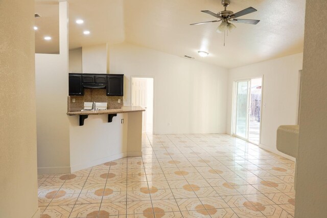 5140 E Belgravia Ave, Fresno, CA 93725 - kitchen featuring vaulted ceiling, a kitchen bar, a ceiling fan, light tile patterned floors, and light stone countertops