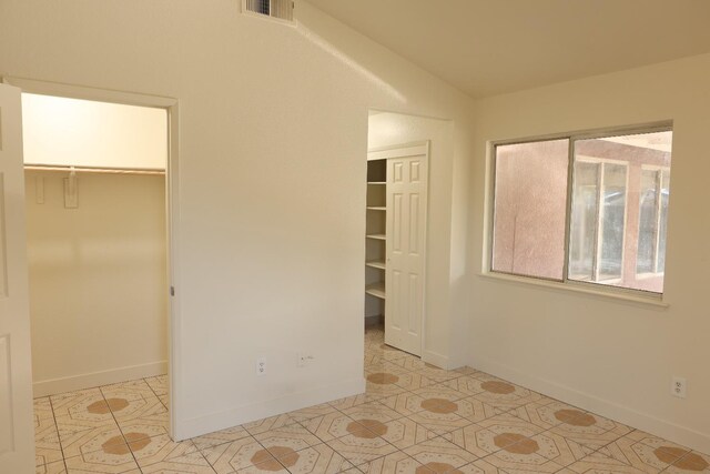 5140 E Belgravia Ave, Fresno, CA 93725 - unfurnished bedroom with vaulted ceiling, tile patterned floors, baseboards, and multiple closets