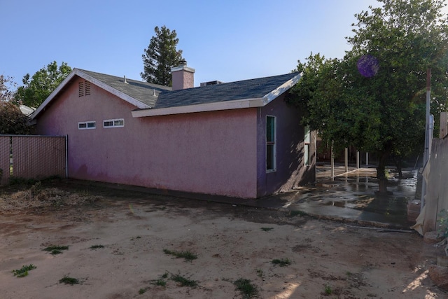 5140 E Belgravia Ave, Fresno, CA 93725 - view of side of home featuring a chimney, stucco siding, and roof with shingles