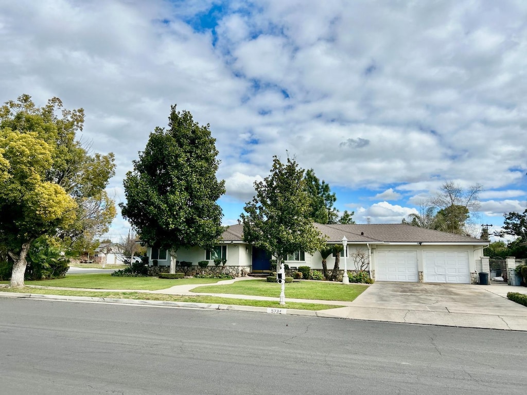 ranch-style house featuring a garage and a front lawn