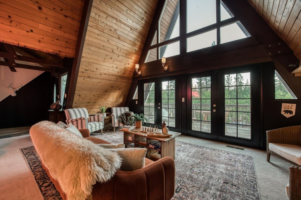 carpeted living room with high vaulted ceiling, wooden walls, beamed ceiling, wood ceiling, and french doors