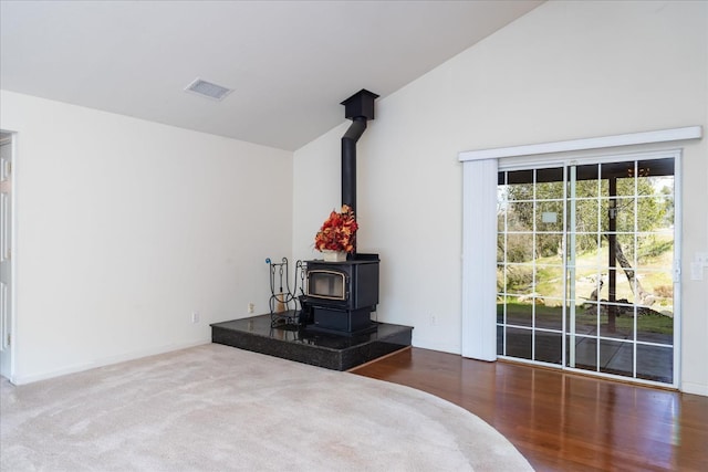 unfurnished bedroom with vaulted ceiling, access to outside, and a wood stove