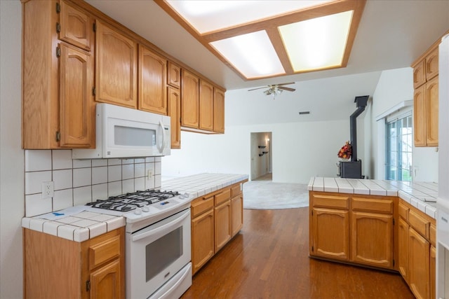 kitchen with a wood stove, tile counters, white appliances, and dark wood-type flooring