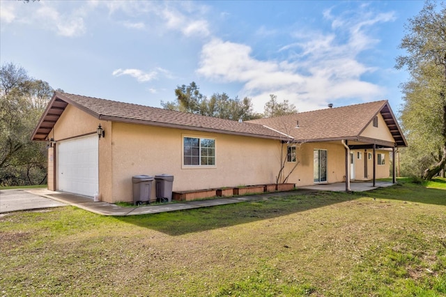 rear view of property featuring a yard, a garage, and a patio