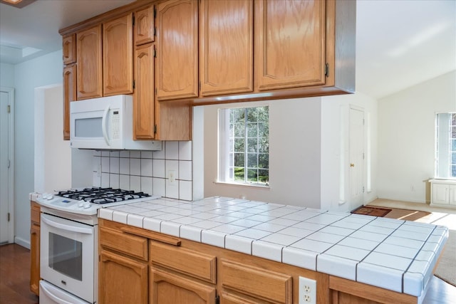 kitchen with tile countertops, white appliances, and decorative backsplash