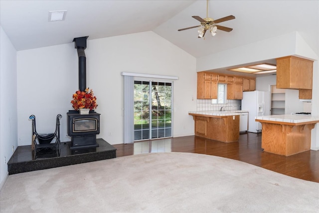 kitchen featuring a kitchen island, a breakfast bar, tile countertops, a wood stove, and white appliances