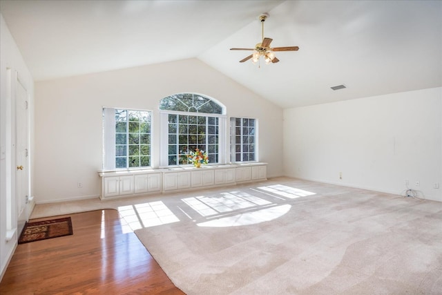 empty room with ceiling fan, high vaulted ceiling, and light hardwood / wood-style flooring