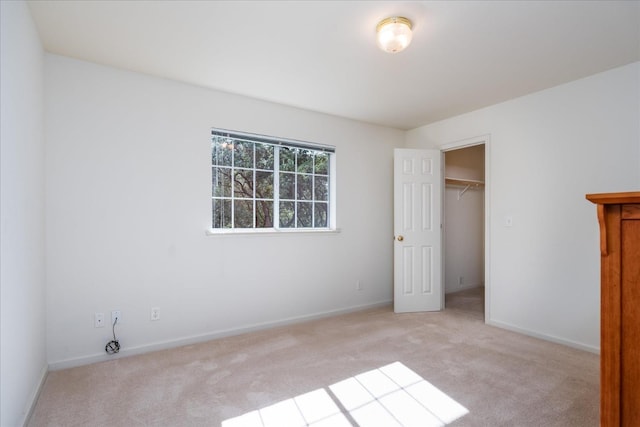 unfurnished bedroom with a spacious closet, light carpet, and a closet